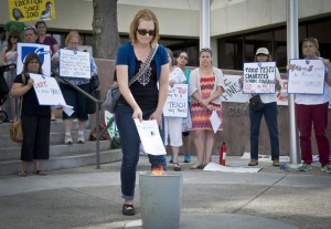 mkb050815h/metro/Marla Brose/050815 Linnea Montoya, a kindergarten teacher at Montezuma Elementary, drops her teacher evaluation into a waste basket with other burning evaluations in front of Albuquerque Public Schools headquarters, Wednesday, May 20, 2015, in Albuquerque, N.M. A group of teachers filled the entrance to APS to participate in the teacher evaluation protest. "It insulted my fellow teachers who mentored me and scored lower," Montoya said. (Marla Brose/Albuquerque Journal)